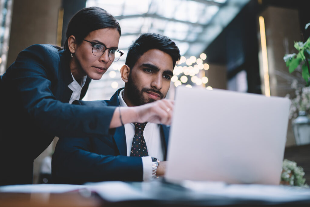 hotel worker pointing on screen working with colleague at table with laptop