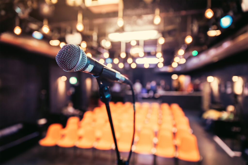 Close up of microphone stand in front of empty seats in the blurry background