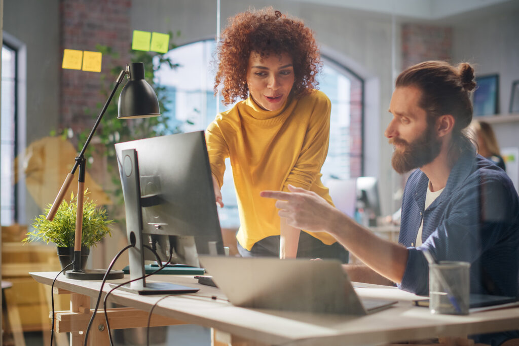 a female manager working with a male colleague on their social media strategy behind a desk 