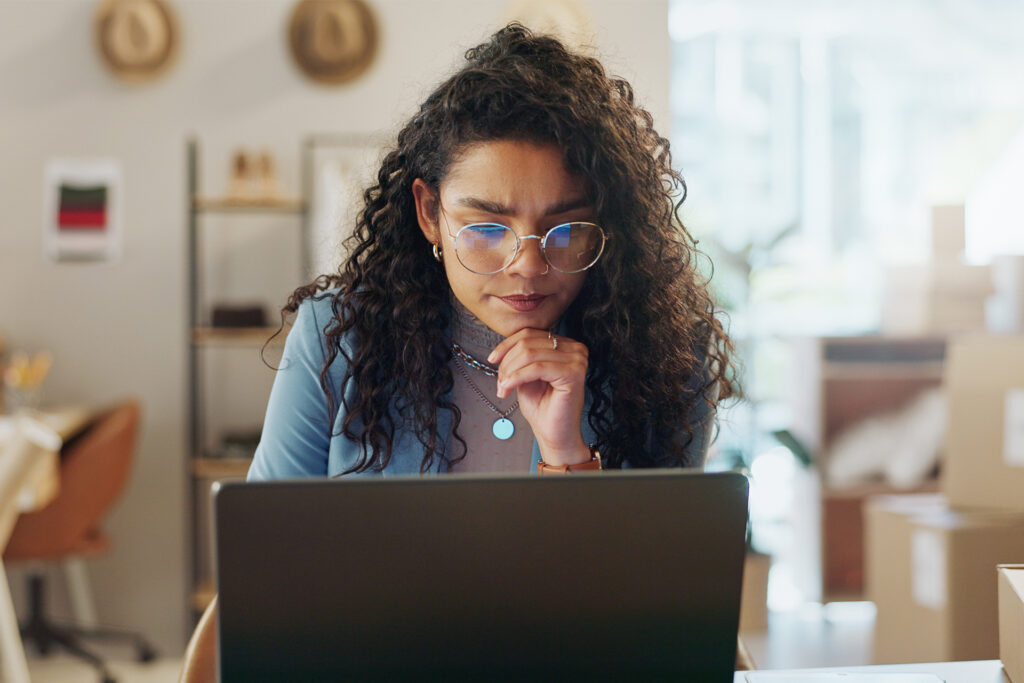 a fashion ecommerce shop owner thinking deeply in front of a laptop