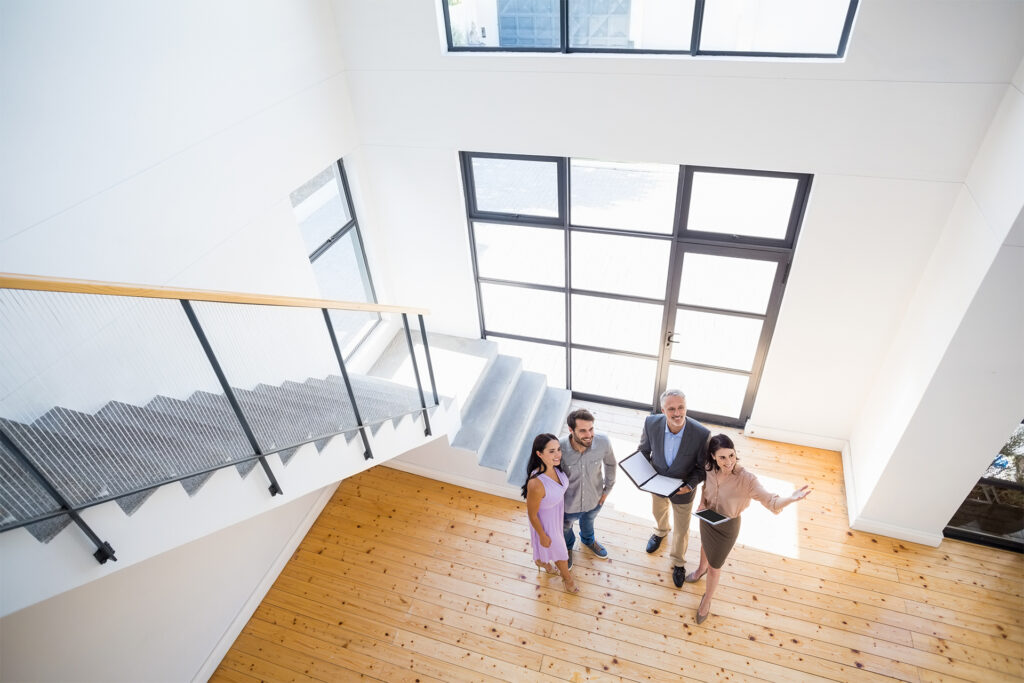 a birds eye view of a couple being shown around a property by two estate agents