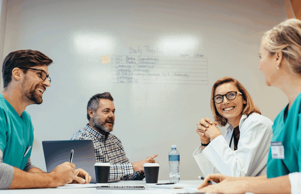 A team of professionals working together in front of a whiteboard on healthcare marketing strategy.