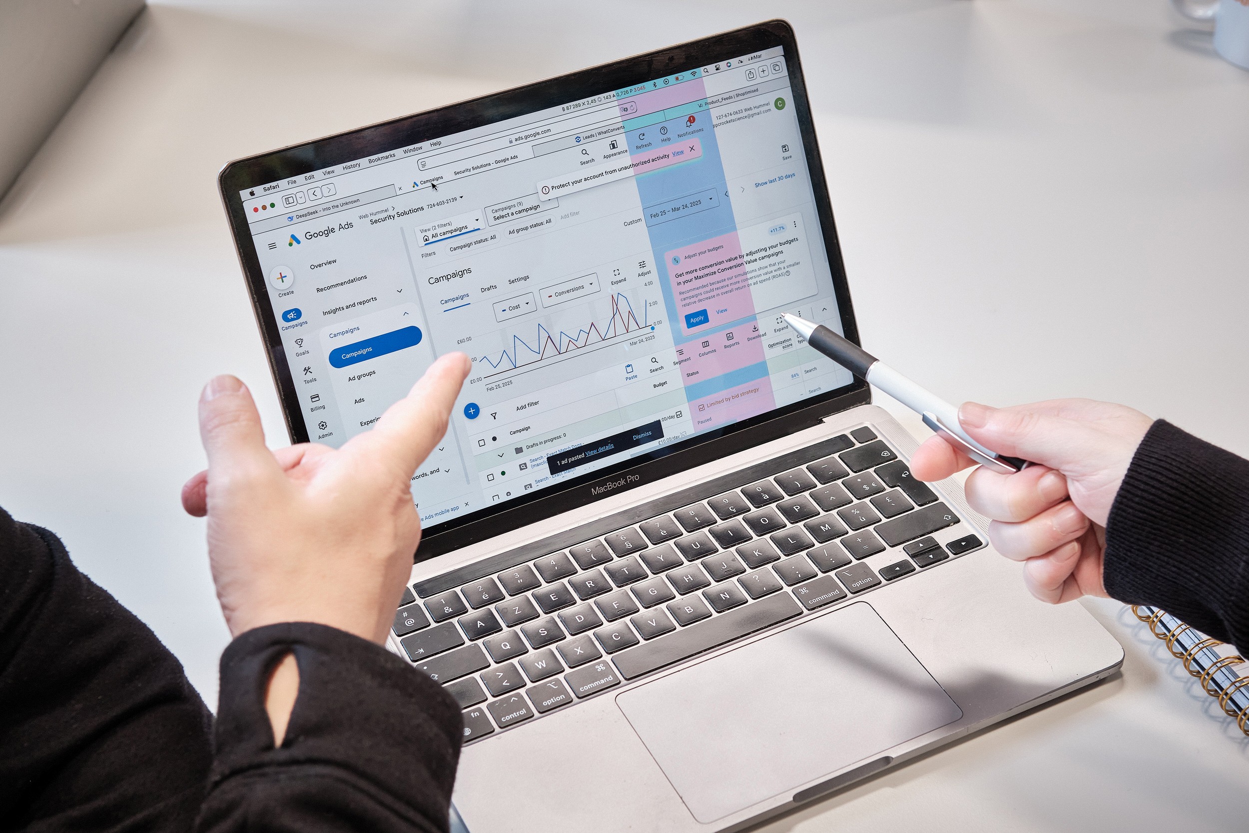 a laptop screen showing google ads campaigns and a marketer pointing to it