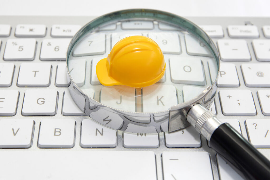 a construction helmet on a white keyboard under a magnifying glass