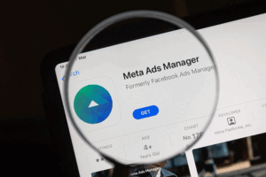 A magnifying glass over the Meta Ads Manager logo, representing trying to figure out what meta advertising is.