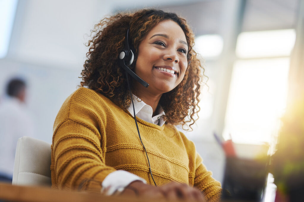 a smiley employee wearing a yellow jumper and a headset in call centre