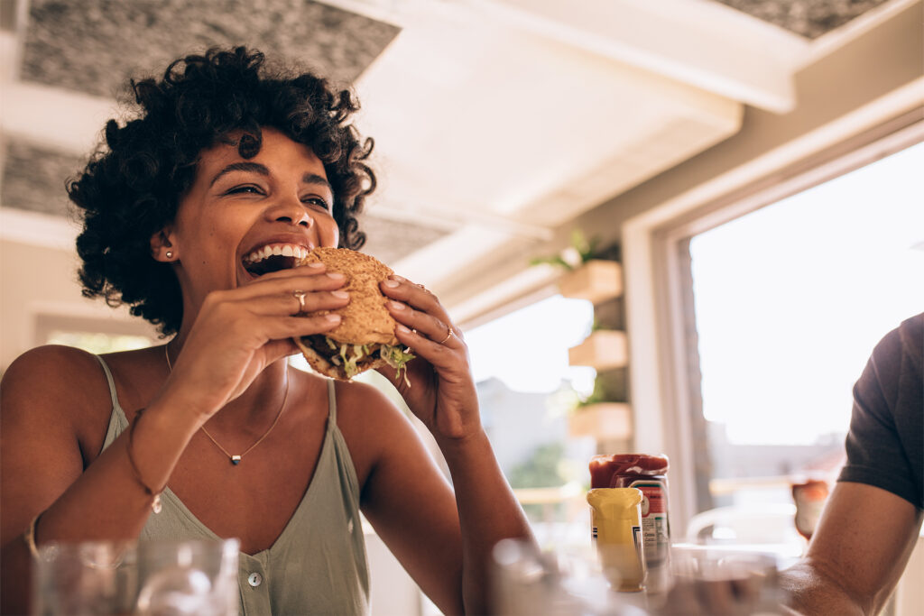 a woman about to bite into a burger at a restaurant with positive google reviews