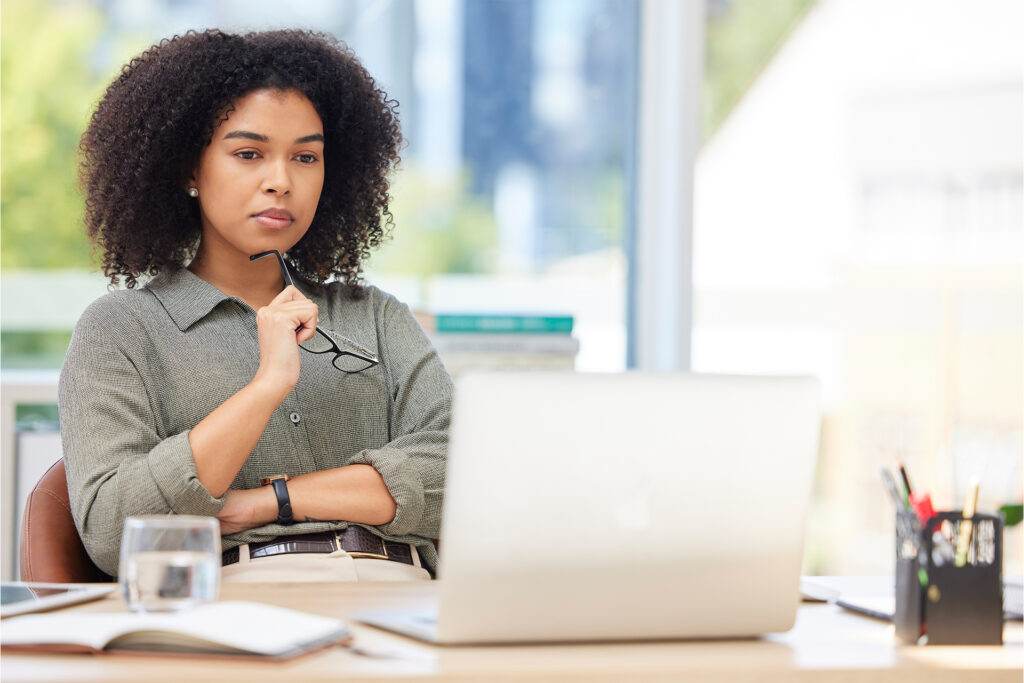 a marketer sitting at her desk looking contemplative with a pair of glasses as she thinks about infographics and seo strategy