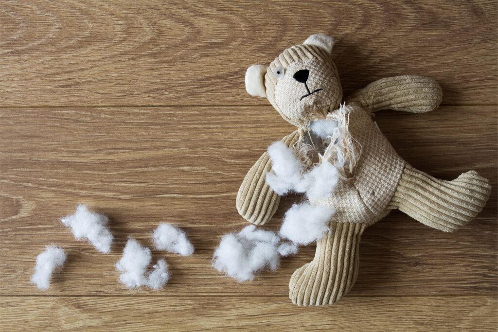 a teddy bear lying on its back on the floor with its stuffing torn out