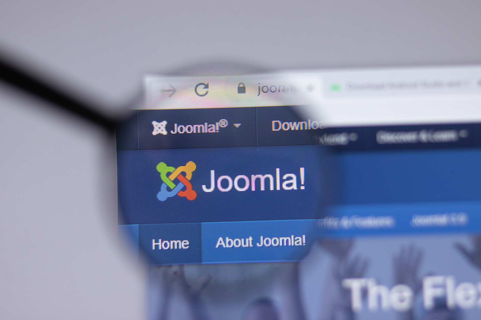 A maginfying glass hovering over the Joomla! website on a laptop screen