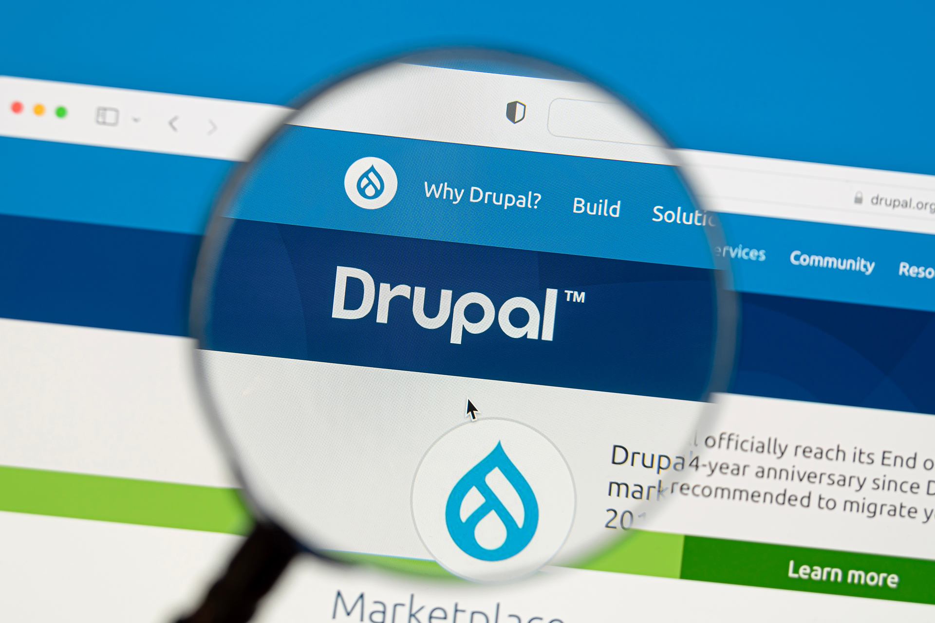 A magnifying glass hovering over the Drupal website on a laptop screen