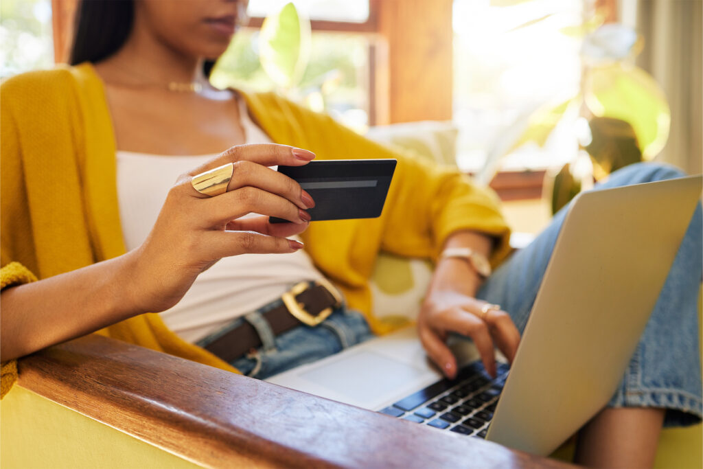 a woman sat in an armchair with her laptop deciding whether to make an online purchase