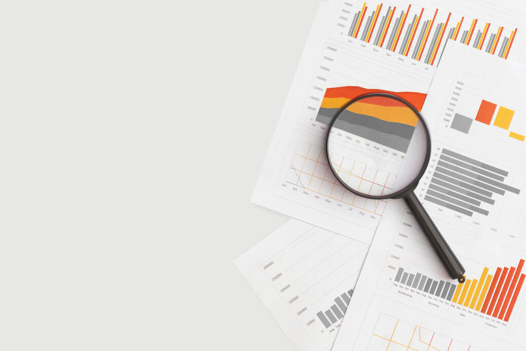 a magnifying glass and a handful of papers demonstrating different charts